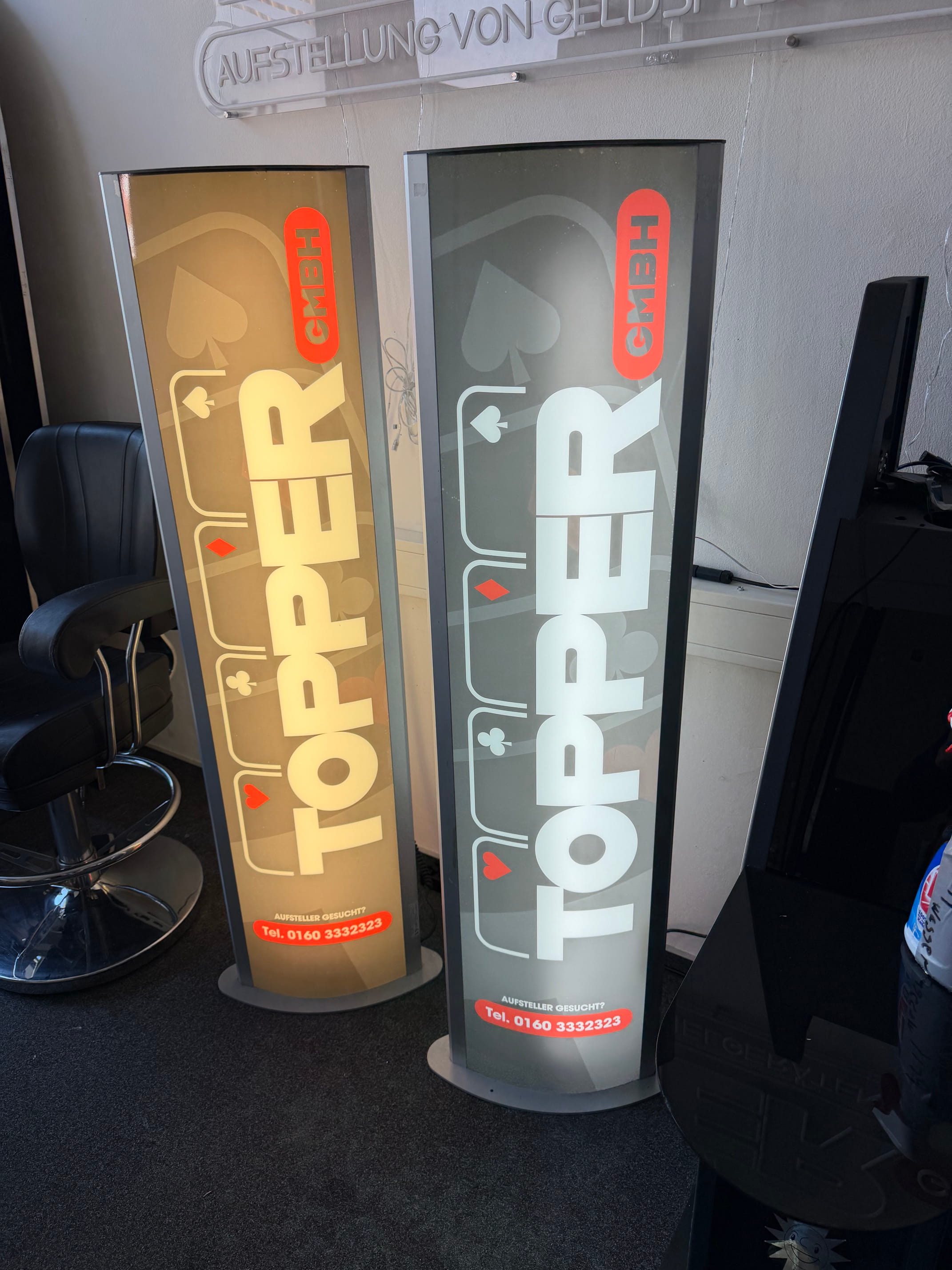 Zwei beleuchtete Topper GmbH Werbedisplays in Gold und Grau