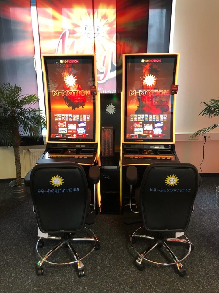 Zwei M-MOTION Premium-Automaten mit goldener Beleuchtung und ergonomischen Gaming-Stühlen