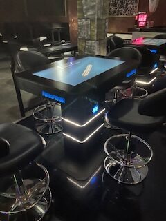 Gaming-Tisch mit blauer LED-Beleuchtung und mehreren ergonomischen Sitzplätzen